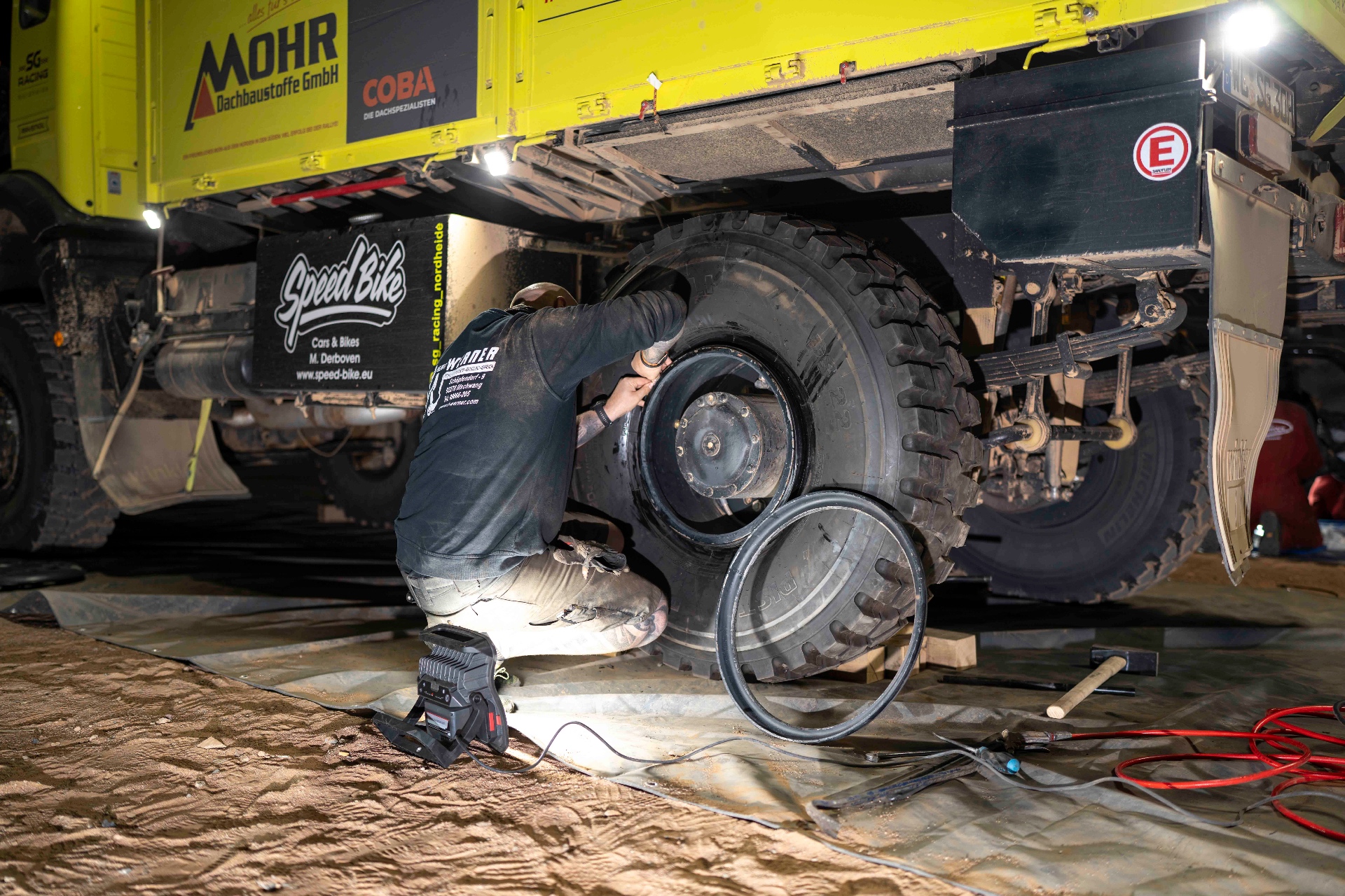 SG Racing mechanic working on a truck tire at night
